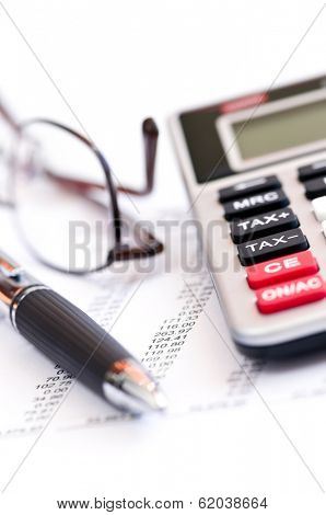 Calculating numbers for income tax return with glasses pen and calculator