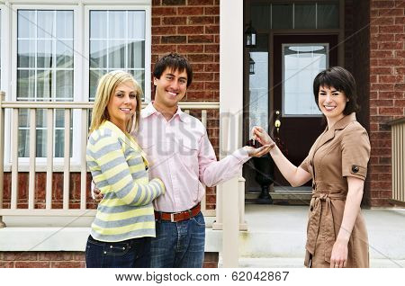 Happy couple getting keys to new house from real estate agent
