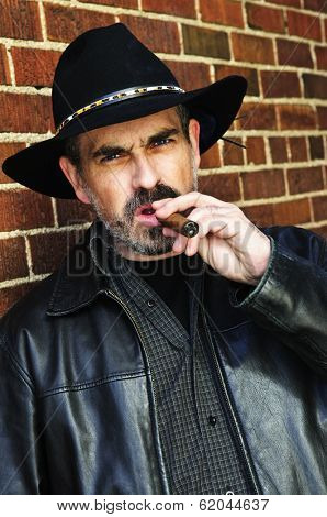 Man with beard in cowboy hat smoking cigar