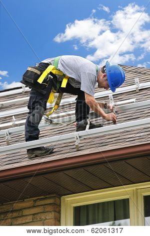 Man installing rails for solar panels on residential house roof