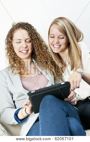 Two young smiling women using tablet computer at home