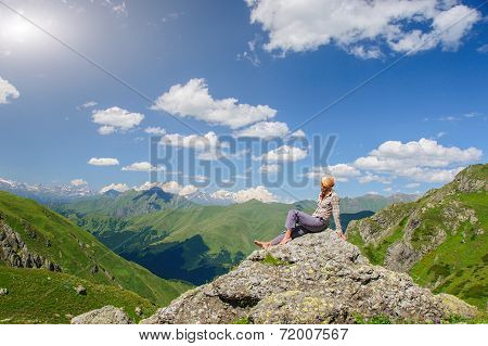 A woman sits on the edge of the cliff and looking at the sun valley and mountains