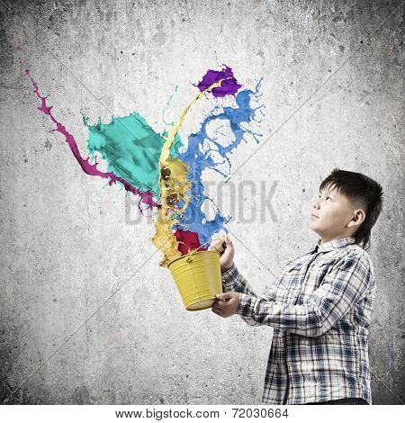 Young boy splashing colorful paint from bucket