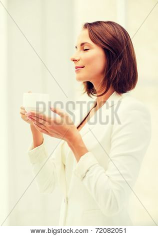 business concept - businesswoman with cup of coffee in office
