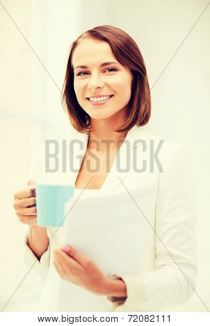 business concept - businesswoman with cup of coffee and folders in office