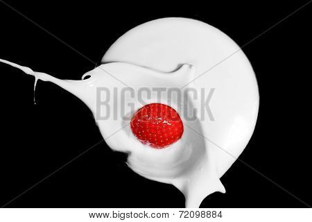 a strawberry splashing in a pool of milk