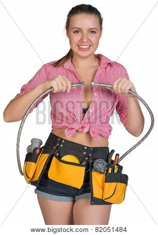 Woman in tool belt holding flexible tap hose