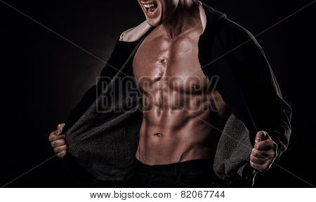 Portrait Of Screaming Bodybuilder With Tight Muscles And His Mouth Open On A Black Background.