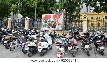 Hanoi Vietnam - Marz 1, 2015: Many Scooters In Front Of Propaganda Billboards