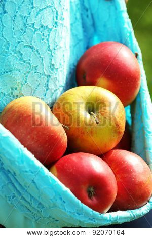 Red apple in hemline of female clothing, closeup