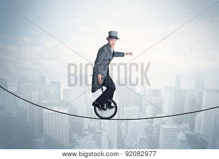 Brave guy riding a monocycle on a rope above cityscape concept