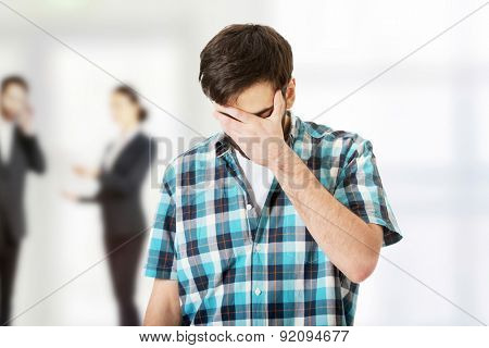 Young upset man covering his face.