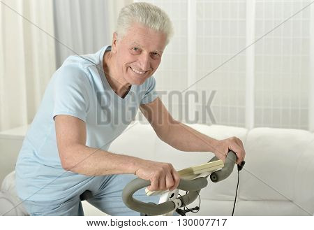 active senior man with bike in gym