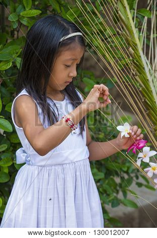 PANCHIMALCO EL SALVADOR - MAY 08 : A Salvadoran girl decorates palm fronds with flowers during the Flower & Palm Festival in Panchimalco El Salvador on May 08 2016