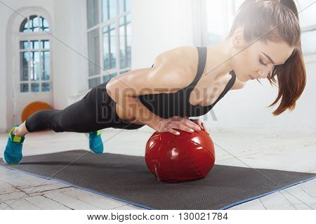 Beautiful young slim woman doing some gymnastics at the gym with medball