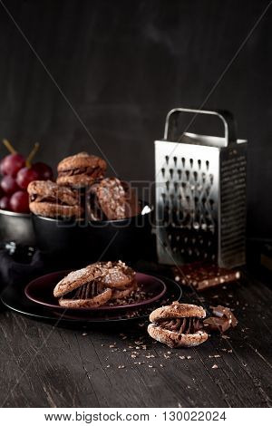 Italian maroni cookies on the plate and bowl with grapes cloth notebook on dark old wooden background