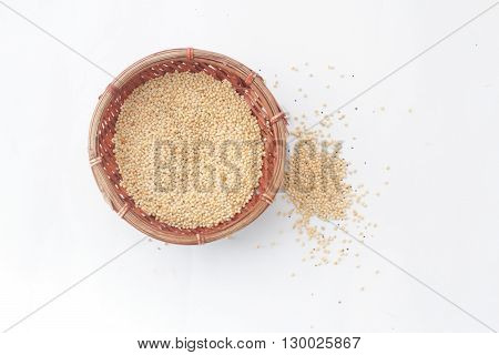 Millet bird's food inside a wicker basket and some scattered outside the basket on isolated white background