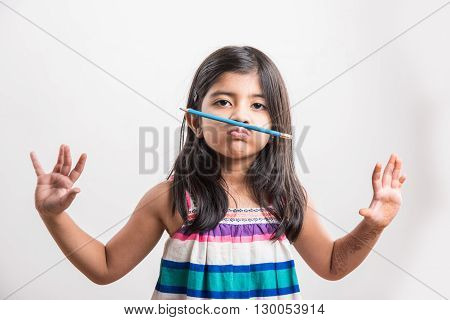 Naughty little indian girl holding a pencil like a mustache. Concept of education. asian girl holding pencil like mustache, isolated over white background