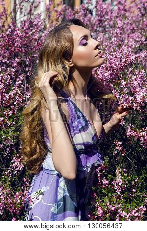 young girl a pink little flowers of almond tree Amygdalus  in Sunny day
