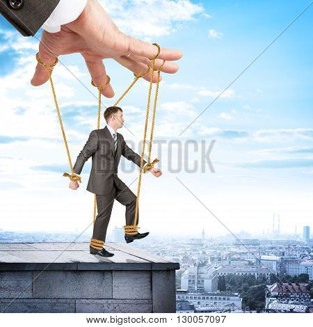 Image of businessman hanging on strings like marionette. Conceptual photography