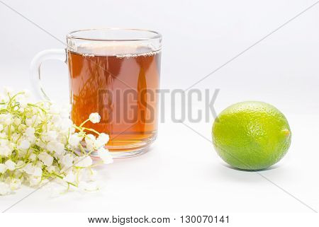 cup of tea with lime and lilies of the valley isolated on white background