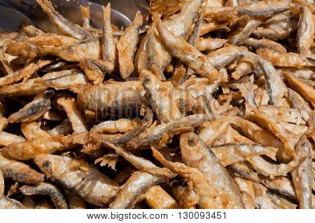 Many small fish fried in oil and ready for food supply in a seafood restaurant