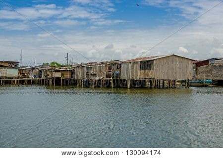 Muisne, Ecuador - March 16, 2016: Muisne town as seen from water, modest wooden houses sitting on poles waterfront pacific ocean, city buildings background and beautiful blue sky.