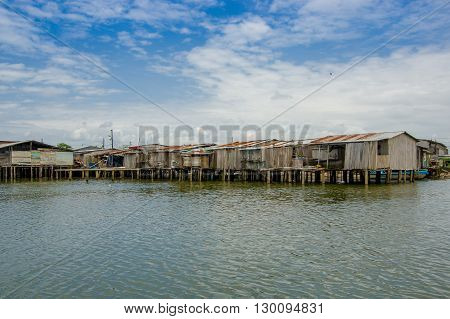 Muisne, Ecuador - March 16, 2016: Muisne town as seen from water, modest wooden houses sitting on poles waterfront pacific ocean, city buildings background and beautiful blue sky.