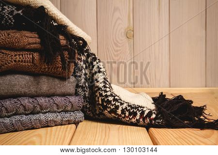 Pile of knitted sweaters on a wooden background