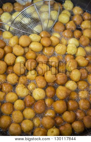 Sweet fried dumplings called Luqaimat in frying pan.