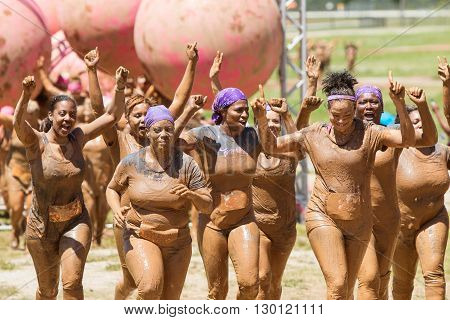 Hampton GA USA - April 23 2016: A group of muddy women celebrate with raised arms as they jog toward the finish line of the Dirty Girl Mud Run obstacle course event on April 23 2016 in Hampton GA.