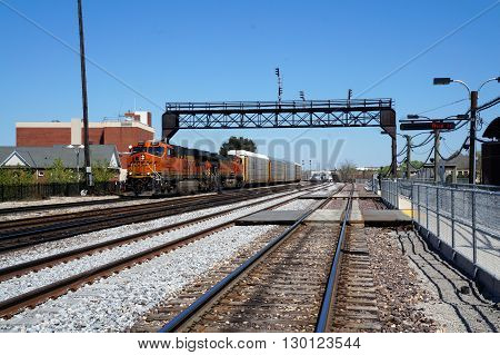 JOLIET, ILLINOIS / UNITED STATES - APRIL 26, 2015: A BNSF train engine pulls freight cars through downtown Joliet.