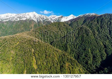 Aerial view of New Zealand mountains. View from above on snow caped mountains with green forest over slopes. New Zealand wilderness landscape of Price range with mount Cloher and Gunn Peak