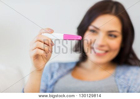 pregnancy, fertility, maternity and people concept - close up of happy smiling woman looking at pregnancy test at home
