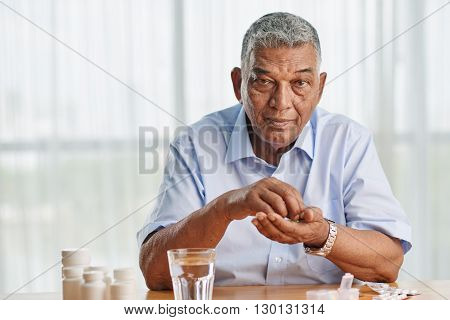 Portrait of elderly Indian man taking medicine every day