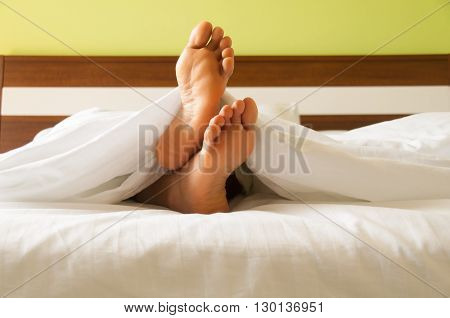 Under the covers with feet showing in a bed