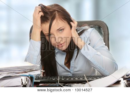 Exhausted female filling out tax forms while sitting at her desk.