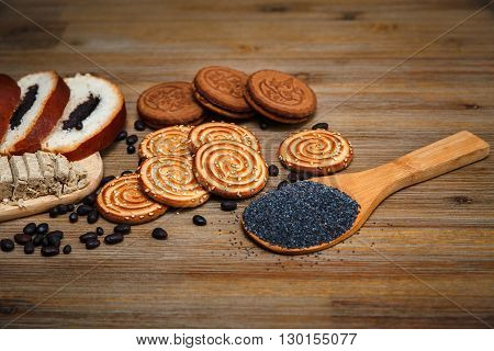 There are Pieces of  Roll with Poppy seed,Cookies,Halavah,Chocolate Peas,Tasty Sweet Food on the Wooden Background