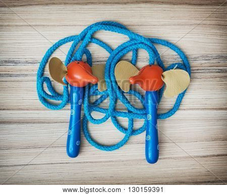 New blue skipping rope on the wooden background. Leisure activity. Healthy lifestyle. Individual sport. Tangled rope.