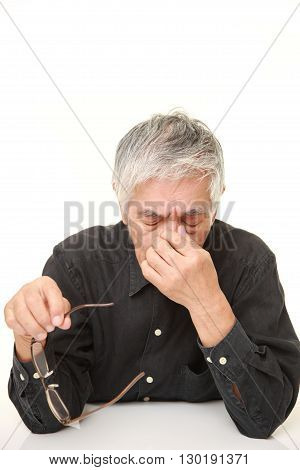 portrait of senior Japanese man suffers from Asthenopia on white background