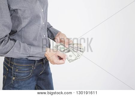 woman blue jeans trousers and grey shirt counting currency money cash one five ten and twenty dollar banknotes in her hands isolated over white background
