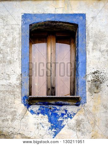 Antique window with blue frame in a village of southern Italy