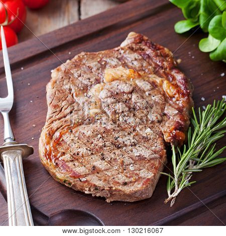 Beef steak with cherry tomato and rosmary on a dark cutting board Wooden background