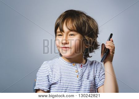 Portrait of happy boy with mobile going surprise on gray background.