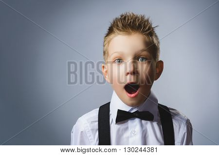 Portrait of happy boy going surprise on gray background.