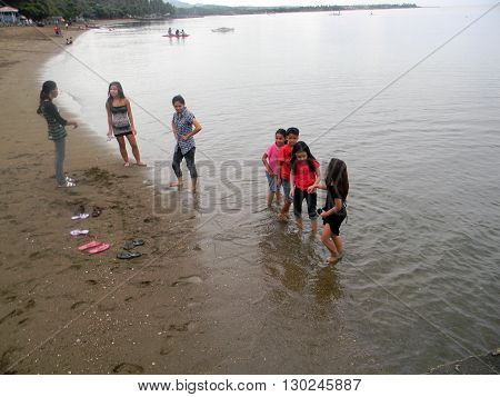 CEBU CITY, CEBU / PHILIPPINES - JULY 30, 2011: Children wade in the water at a beach in Cebu.