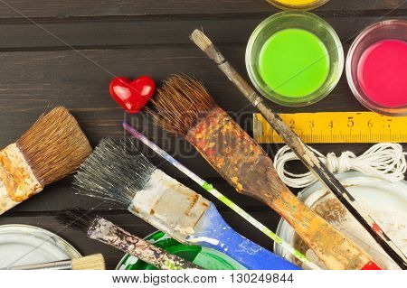 Brushes and paint on a wooden table. Painter tools. Workshop painter. Needs painting. Sales painting needs. Clutter on the workbench. Sales of color. Advertising on painting.