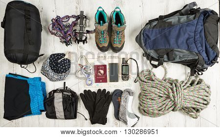 Outfit of traveler climber student teenager. Overhead of essentials for modern sport young person. Different objects on white wooden background