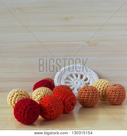 Red, orange and yellow crochet beads and white vintage elements of Irish crochet. Cotton yarn for knitting, crochet. Crochet doilies, crochet pattern coasters on bamboo background
