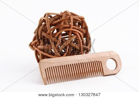 horizontal front view of a wooden comb next to a ball of twisted brown wood branches isolated on white background